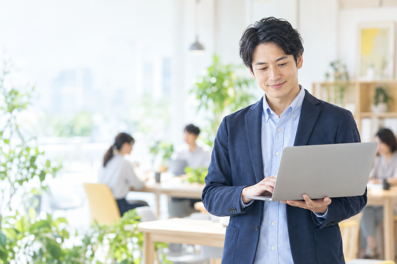 明るいオフィスでノートパソコンを使う爽やかな会社員